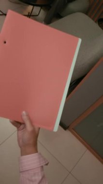 Tanımlanamayan şirket yöneticisinin, modern ofiste dizüstü bilgisayarda çalışmaya odaklanmış siyah erkek çalışana elinde belgelerle pembe klasörü teslim edişinin dikey görüntüsü.