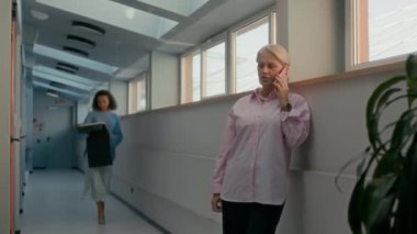 Modern ofis koridorunda telefonla konuşan Kafkas 'lı, meşgul CEO kadına tekstil numuneleri gösteren orta boy bir çift ırklı kadın tasarımcı.