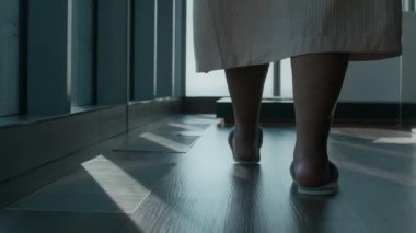 Lüks banyo paspasının üzerinde, panoramik pencere manzarasına yaslanmış, yumuşak, rahat terliklerini ve bornozunu çıkararak zarif bir şekilde banyo paspasına basan, tanınmayacak kadar yavaş bir kadın.
