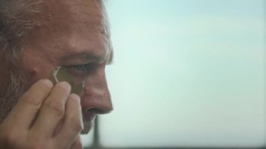 Modern ortamda sabahları cilt bakımını yaparken hidrojel göz bandı sürerken beyaz saçlı yakışıklı bir adamın orta boy yakın çekimi.