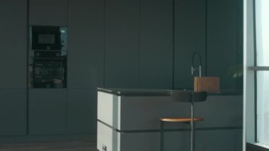Minimalist, koyu gri mutfak, gösterişli dolaplar ve bar taburesi olan merkez adanın iç çekimleri yok.