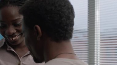 Genç, neşeli siyah çift, hamilelik keşfinin hassas anını evcil atmosferde paylaşıyor. Kocasına sevgiyle sarılırken pozitif hamilelik testi uygulayan bir kadın.