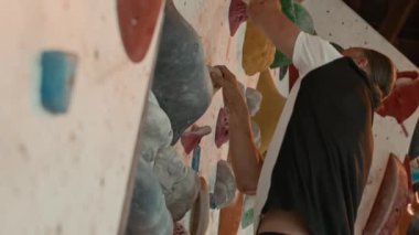 Orta yaşlı Kafkas sporcusunun spor kıyafetleri içinde kaya tırmanışı yaparken ki yan görüntüsü.