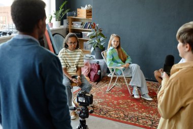 Bir grup gencin stüdyoda birlikte podcast ya da video kaydettiği sahne arkası çekimleri. Öğretmen de yardım ediyor.