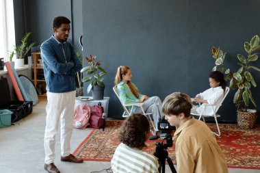 Bir grup gencin sahne arkasında podcast ya da video kaydetmek için stüdyoyu kurarken öğretmenlerin yardım ettiği sahneler, kopyalama alanı