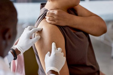 Tanımlanamayan Afrikalı Amerikalı bir doktorun klinikteki kadın hastanın omzunu muayene etmesi ve acılı bir bölgede fotokopi çekmesi.