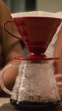 İş yerinde tezgahta duran tanınmamış kafe çalışanları damlayan kahve yaparken konuşuyorlar.