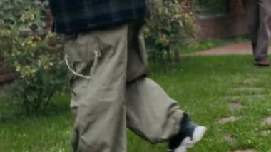 Aktif büyükbaba, yapraklı ağaçlar ve taze yeşil çimlerle dolu kır evlerinin arka bahçesinde iki torunuyla futbol oynuyor.