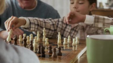 Kafkasyalı neşeli büyükbaba ve iki akıllı torunu rahat bir aile ortamında ahşap masada satranç oynuyorlar. Başarılı bir hamle yaptıktan sonra torununa beşlik çakıyorlar.
