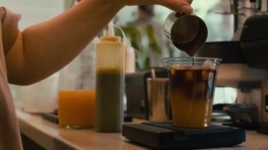 Tanımlanamayan bayan barista, yabanarısı kahvesine portakal suyu katıyor, yakın çekim.