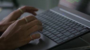 Programın kodunu yazan parmaklarıyla yüzükler takan ve akşam ofiste dizüstü bilgisayarla çalışan genç kadın programcının yavaş çekimleri.