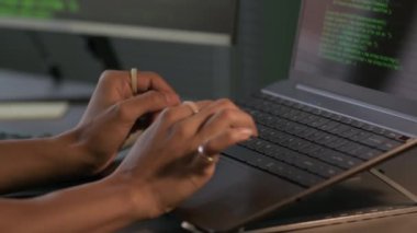 Modern programcılar ofisinde geceleri aşırı çalışan genç bir kadın programcının parmaklarında yüzüklerle dizüstü bilgisayarında program kodları yazarken yakın plan çekimleri.