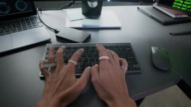 Gece modern programcılar ofisinde bilgisayar üzerinde çalışan ve daktilo eden genç bir kadın programcının POV eğik görüntüsü.