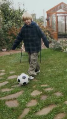 Serayla yemyeşil çimlerde futbol oynayan iki çocuğun yemyeşil bahçede birlikte zaman geçirdiği dikey bakış açısı.