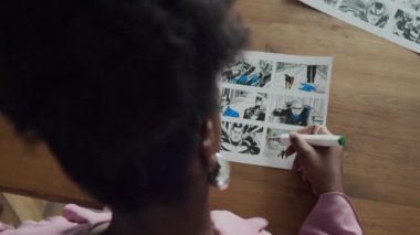 Çalışma masasında çizim tahtası kağıtlarıyla çalışırken siyah kadın çizerlerin mavi fosforlu kalemle üst aşağı görüntüsü