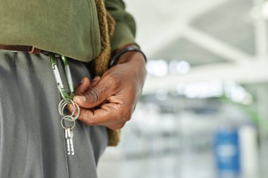 Close up on hand of Black man holding keys of rented self storage unit hanging from carabiner at warehouse, copy space clipart