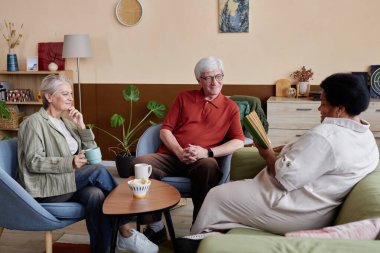 Yaşlı insanların, içeride Afrikalı Amerikalı kadınlarla kitap kulübü tartışmalarından keyif aldıkları ve arkadaşlarına sesli kitap okudukları portre.