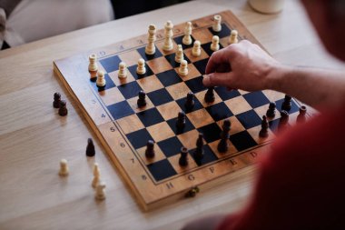 Üst görünüm, el hareketli piyon parçasına odaklanmış, satranç oynayan tanınmayan bir adamın yakın görüntüsü