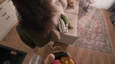 Melez bir kadınla erkek arkadaşının, marketten birlikte döndükleri, masada taze meyve ve sebze paketlerini açıp sohbet ettikleri video görüntüsü.
