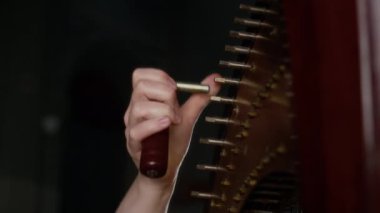 Genç kadın ellerinin, klasik parlak arpı akort anahtarıyla akort ederken çekilmiş görüntüsü.