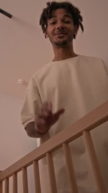 Dikey çekim, genç gülümseyen melez bir adam rahat çocuk odasına giriyor, bebeğine el sallıyor, bebeği beşiğinden dikkatlice çıkarıyor ve nazikçe kollarında sallanmaya başlıyor.