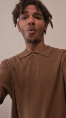 Sevgili sevgilisinin elini tutan neşeli melez adamın dikey görüntüsü daire etrafında dönüyor ve eğleniyor.