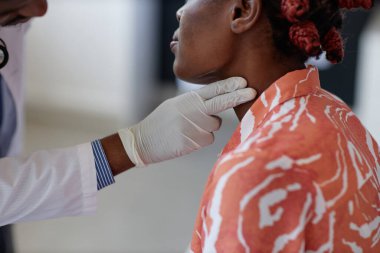 Klinikteki kontroller sırasında lenf düğümlerini inceleyen, tanıması mümkün olmayan bir doktorun yan görüntüsü.