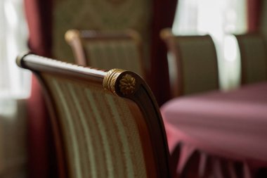 Close up detail shot of curved back of antique wooden chair with gold accents and ornaments in defocused classic interior, copy space clipart