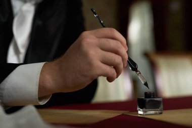 Klasik ayarlarda harfler yazarken, erkek el dolmakalemini mürekkebe batırırken kenar görünümü kapat, boşluğu kopyala