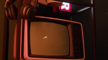Çatı katında pembe vintage TV, asılı kulaklıklar, fotoğraf çerçevesi, çiçek saksısı ve hava neon tabelaları ile çekilen hiç kimse modern podcast stüdyosunda modaya uygun bir görünüm ve rahat bir atmosfer yaratmasın.
