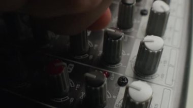 Kayıt stüdyosundaki gri karıştırma konsolunda tanımlanamayan ellerin ses sinyallerini karıştırdığı yakın çekim