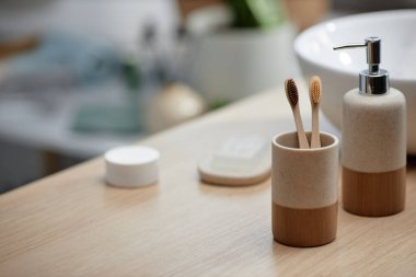 Banyo lavabosunun yanındaki seramik tutacağa yerleştirilmiş bambu diş fırçaları, sıfır atık konsepti, kopyalama alanı