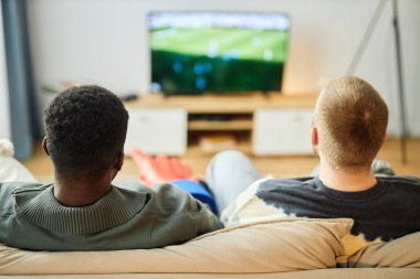 İki yetişkinin TV 'de futbol maçı izlerken kanepede otururken, fotokopi çekerken.