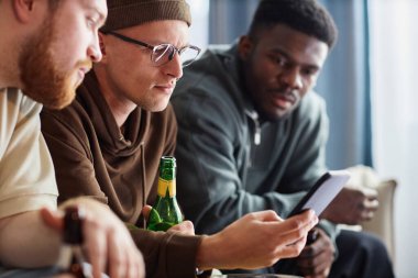 Çevrimiçi maç izlerken akıllı telefon ekranına bakan üç sporcunun yan görünüm portresi