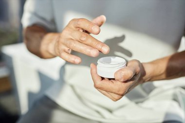 Ellerinde plastik güzellik kremi olan olgun bir adamın ellerine yaklaş. Banyoda yüz bakımı yaparken cilt ürünlerini besliyorlar. Boşlukları kopyalıyorlar.