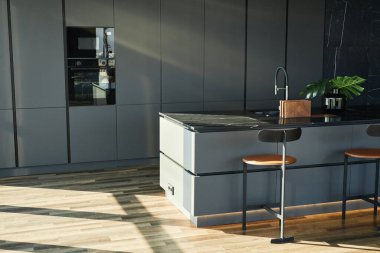 İskandinav endüstriyel tarzında güneşli mutfağın içi. Ortasında lavabo olan işlevsel tezgah yemek pişirmek için rahat atmosfer yaratıyor, kopyalama alanı yaratıyor.