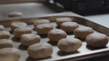 Yemek pişirmek için hazırlanan, düzgün yerleştirilmiş hamur toplarıyla dolu bir tepsiyi yakından çeken kimse yok.