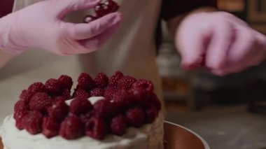 Pembe eldivenli tanınmayan fırıncının yakın çekimi. Dönme dolapta taze böğürtlen süslüyor.