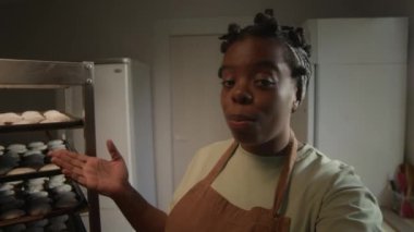 İş mutfağındaki paslanmaz çelik raflarda dinlenen yeni pişmiş hamur işlerini gösterirken önlüklü, hevesli, genç Afrikalı Amerikalı kadın şefin pov çekimi.