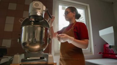 Düşük açılı Kafkas kadın hamur işi işletim standı karıştırıcısı paslanmaz çelik karıştırma kabında malzemeleri karıştırırken aynı zamanda profesyonel mutfak düzeninde çalışıyor.