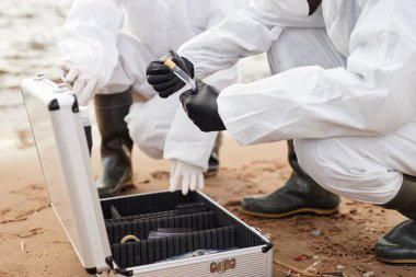 İki bilim adamının test kitini açarken suyun yanında araştırma yaparken ve test tüpleri tutarken kapatın, boşluğu kopyalayın.