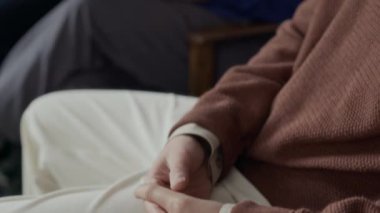 Gözlüklü gencin el ele tutuşup grup terapisi sırasında genç siyahi psikologla aynı ortamda oturduğu sırada güvensiz hissettiği pozlar.