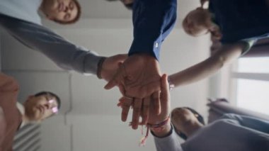 Grup liderinin çeşitli gençlerle el ele tutuşup olumlu takım motivasyonu, birlik hissi, destek ve işbirliği yaratırken görüntüsü altında.