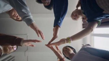 Çok ırklı gençlerin el ele tutuşup onları kaldırarak birlik ve takım desteği yarattıkları genç siyahi kadın yöneticinin alt görüntüsü.