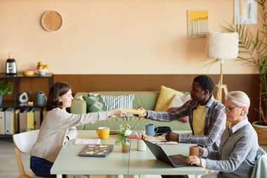 Siyahi duvarlara karşı ortak çalışma sırasında toplantı masasında oturan genç Afrikalı Amerikalı bir adamın kadın meslektaşı kitabını geçirmesi, kopyalama alanı