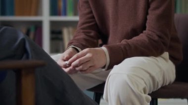 Genç bir adamın yüzüğünü sürterek farklı parmaklarına taktığı, tanınmayan bir danışmanın önünde kendini savunmasız hissettiği görüntüler.