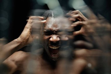 Siyah adamın portresi öfkeyle başını tutarak bağırıyor bastırılmış duyguların patlamasını yaşıyor, karanlık stüdyoda akan su damlalarıyla birlikte sert ışıkla yansıtılıyor