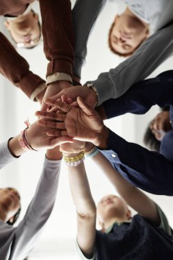 Okulda takım oluşturma egzersizi sırasında el ele tutuşan ve el ele tutuşan bir grup çocuğun alt çekimlerinden dikey olarak avuç içlerine odaklan
