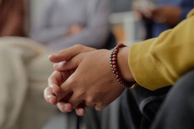 Çocuklar için düzenlenen destek grubu toplantısında elleri birbirine kenetlenmiş siyahi çocuğun yan görüntüsü.