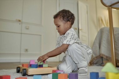 Küçük siyahi çocuğun rahat ev kıyafetleri giyip yatak odasındaki ahşap yapı taşlarıyla oynarken, kamera flaşı, fotokopi odası...
